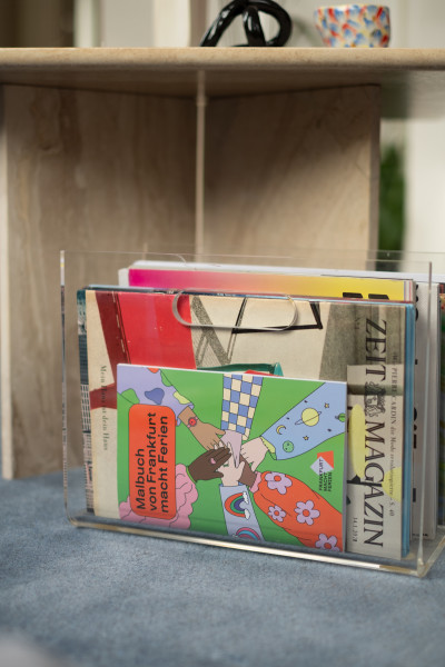  Transparenter Zeitungsständer mit verschiedenen Magazinen. Das Cover des Malbuches ist zu sehen